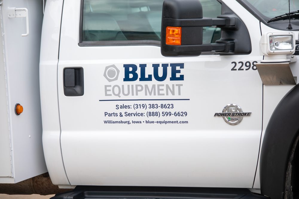 The Blue Equipment logo and phone numbers on the field service truck door