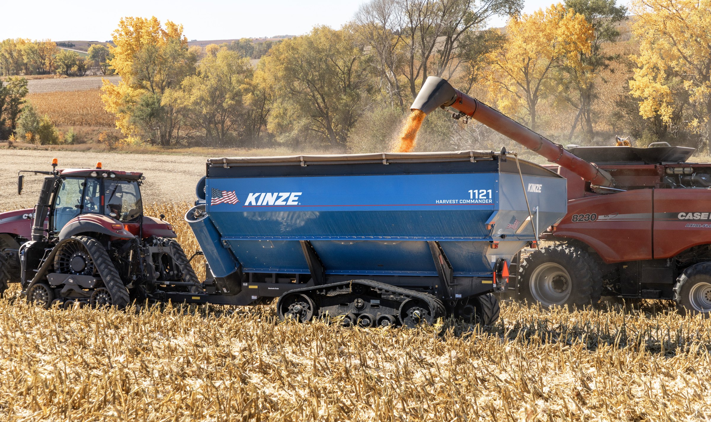 A Kinze 1121 Harvest Commander grain cart on tracks, taking corn from a combine at harvest