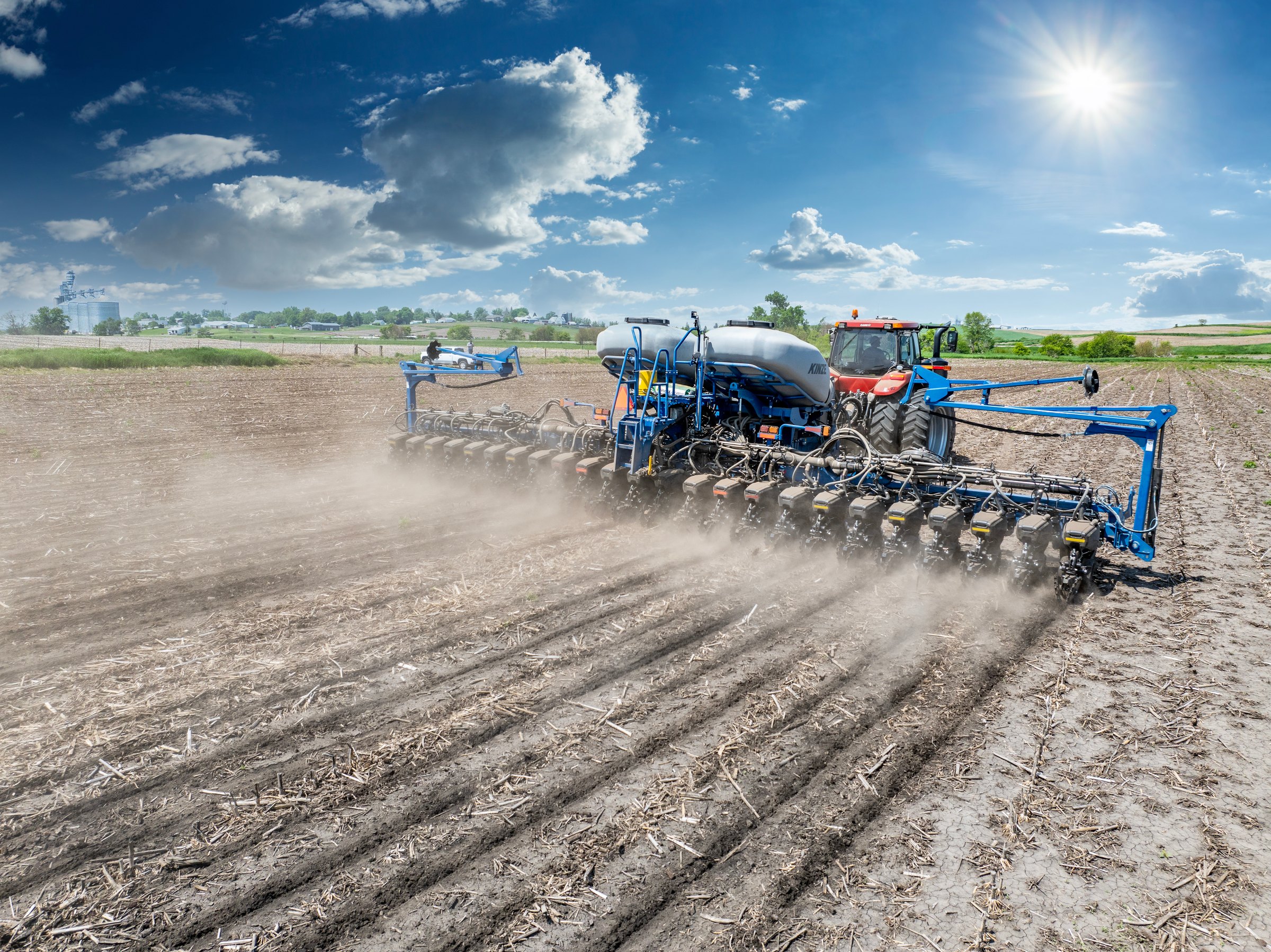 A Kinze 5700 planter planting a field under a bright spring sky